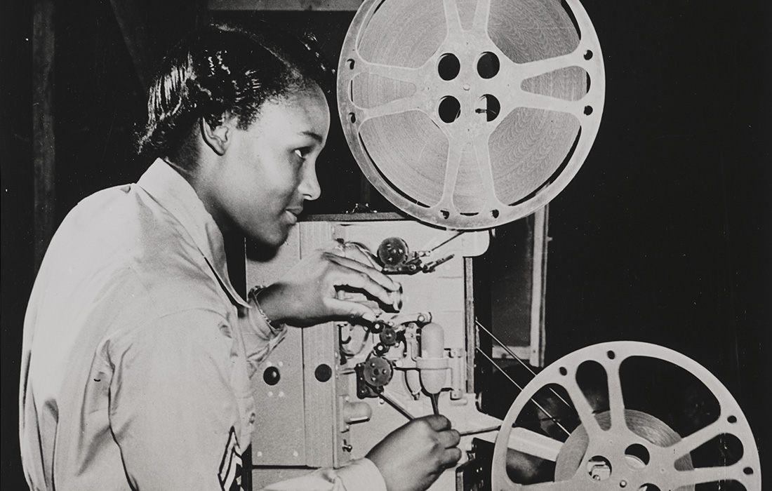 A student learning how to operate an old film projector