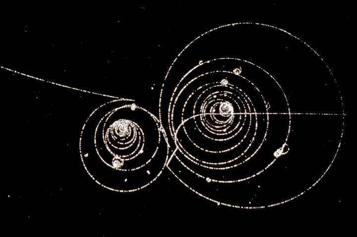 Decaïment d’un kaó positiu en el seu vol. Les partícules en què decau es poden veure dibuixant espirals en el camp magnètic d’una cambra de bombolles (CERN).