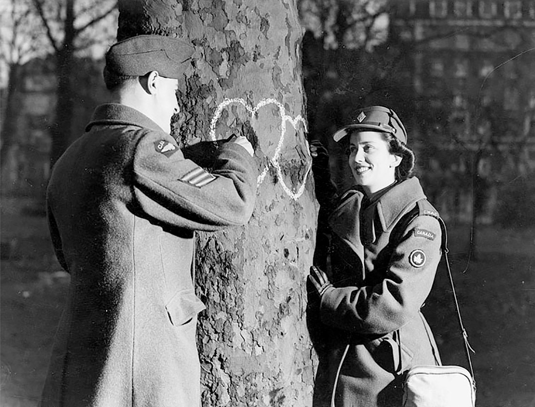 Young couple chalking hearts onto a tree, 1944