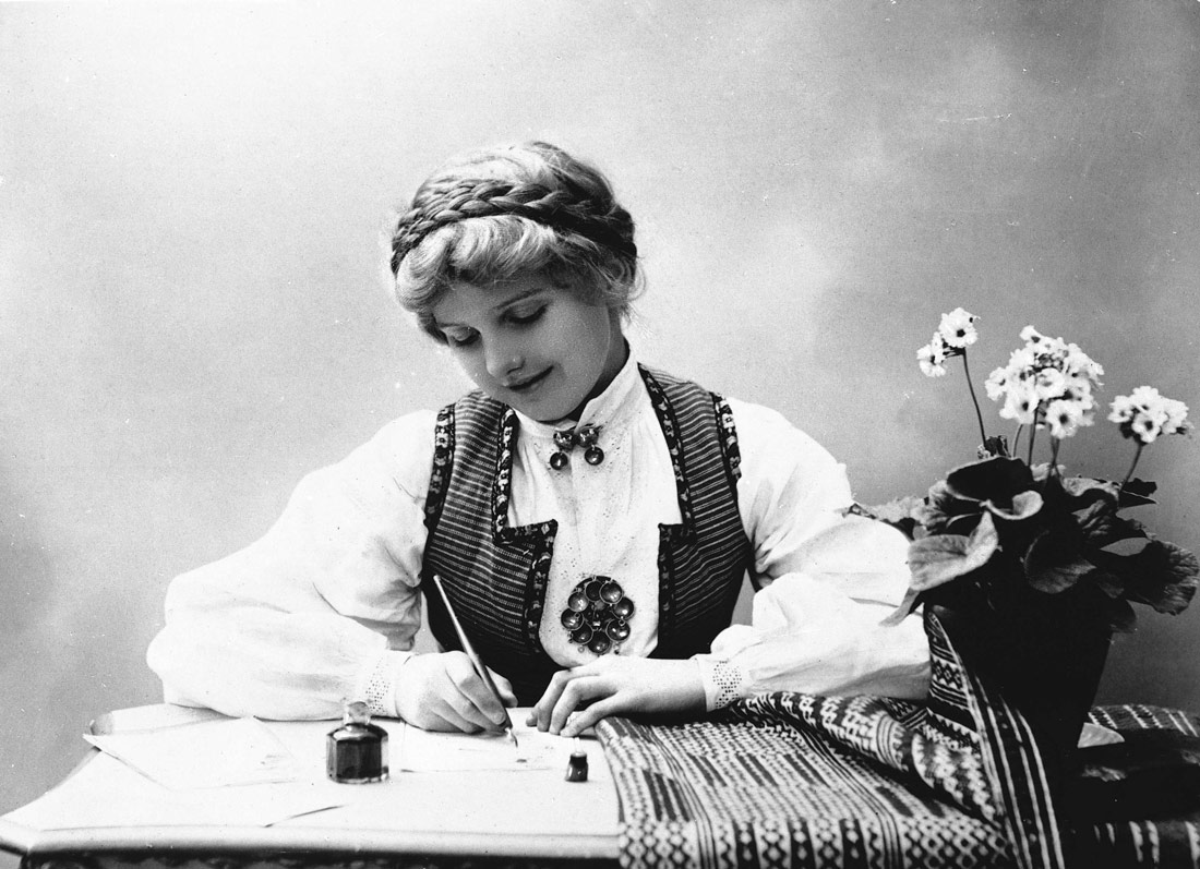 Una mujer escribe una carta con pluma y tinta