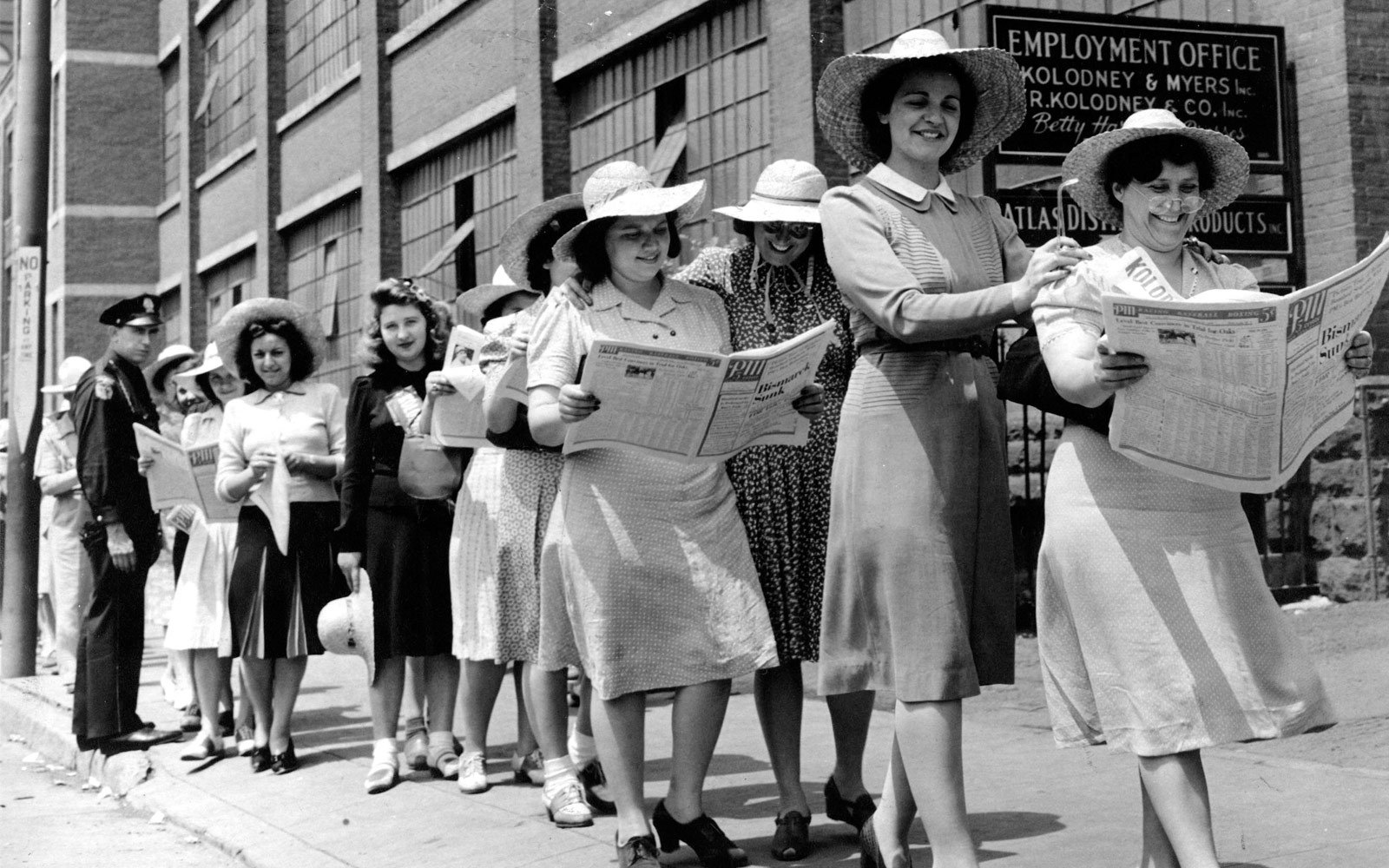 Mujeres de un piquete en fila leyendo el diario.