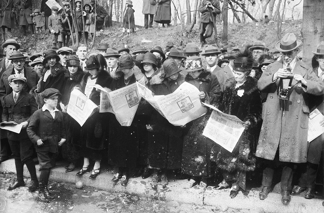 Group reading newspapers with news of death of Woodrow Wilson