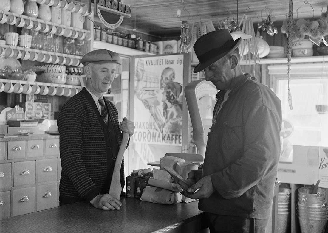 Un comerciante y un cliente considerando comprar un hacha o un mango de hacha. Leaby, Suecia, 1940