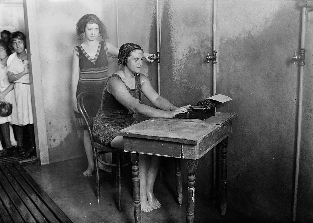 Woman using typewriter in shower, 1922