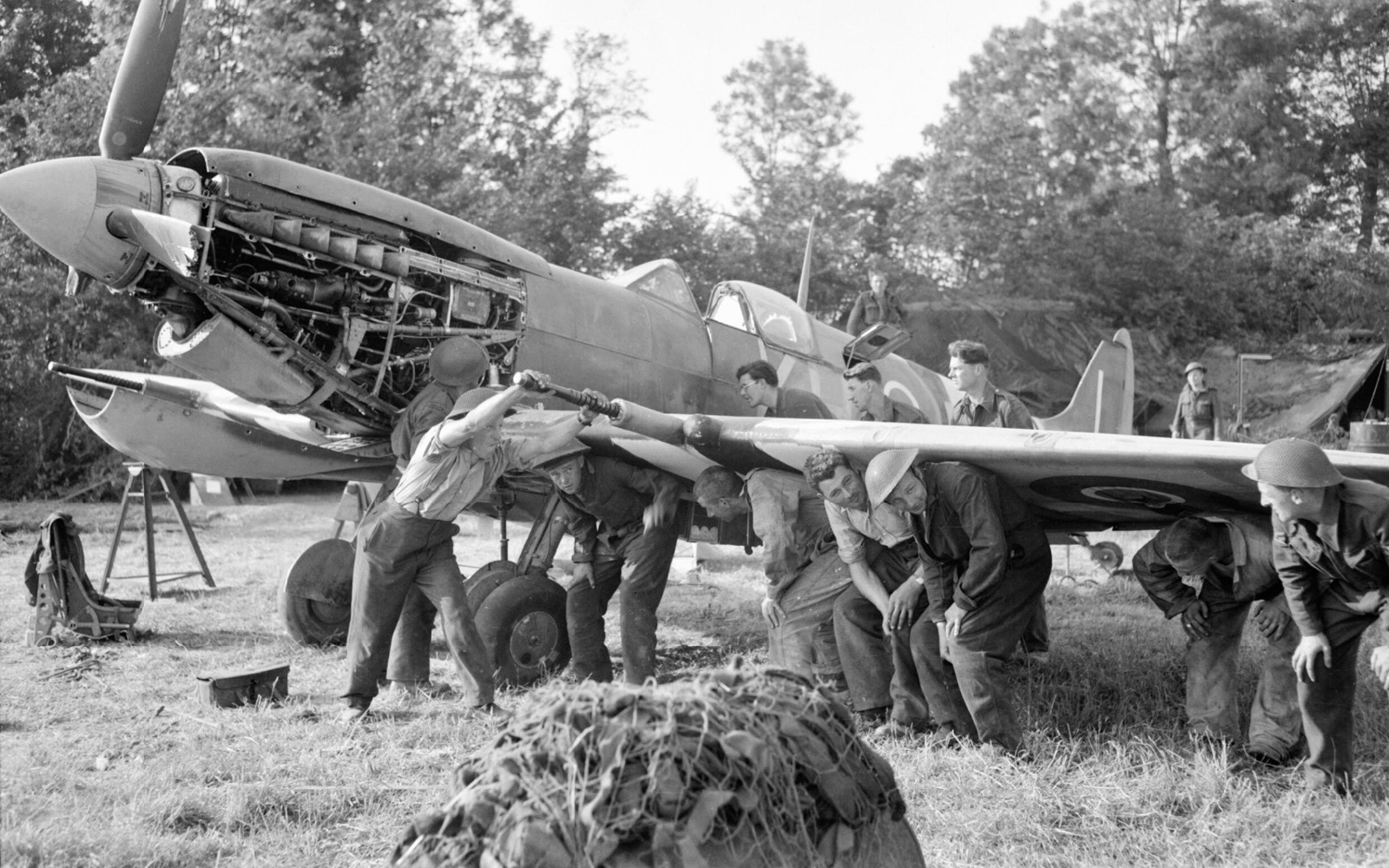 Men of an RAF Repair and Salvage Unit working on a damaged Supermarine Spitfire Mk IX of No 403 Squadron, Royal Canadian Air Force, at a forward airstrip in Normandy, 19 June 1944