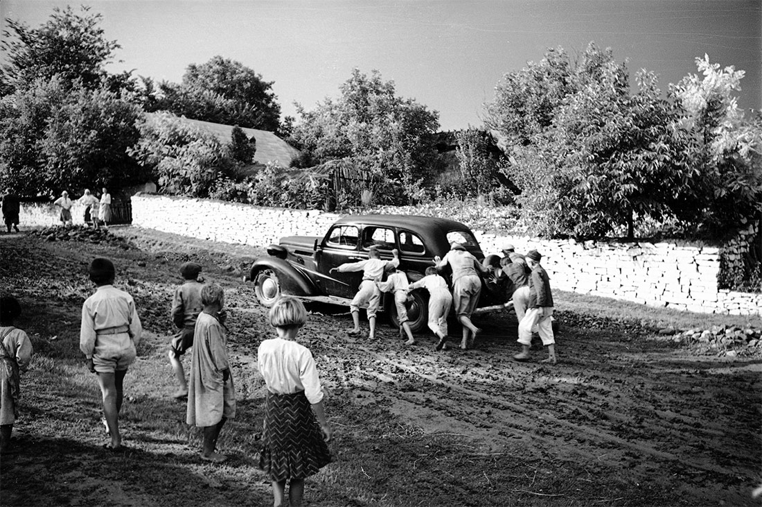 Un grupo de personas empujando un coche atascado en el barro. 1938, Horodenka