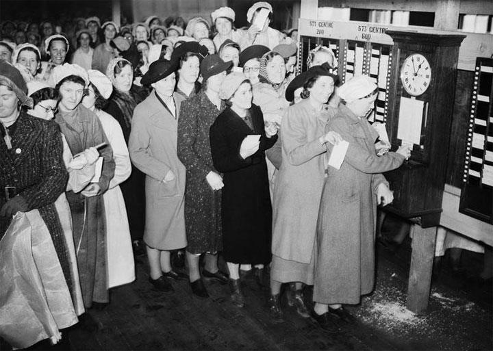 Un grup de treballadores fent cua per fitxar en una fàbrica d'armes. Gran Bretanya, 1940.